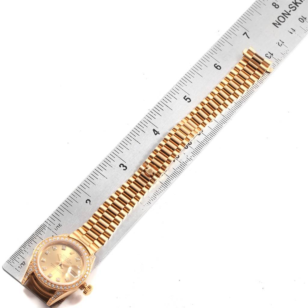 The image shows a Rolex President 79188 Women
s Yellow Gold Champagne Dial 79188 Women
s Yellow Gold Champagne Dial model watch laid flat with a ruler beside it, displaying the watch face and full band.