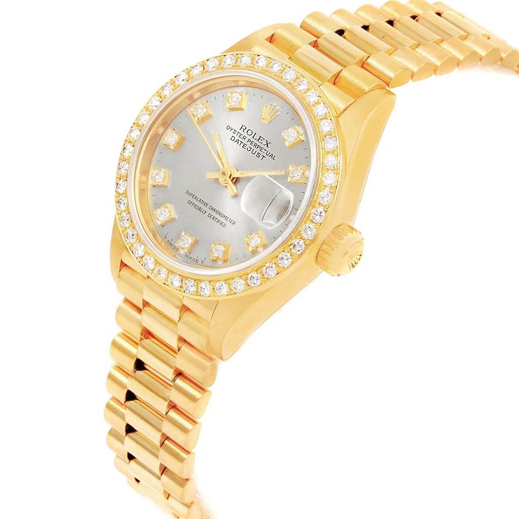 The image shows a Rolex President 69178 Women
s Yellow Gold Silver Dial 69178 Women
s Yellow Gold Silver Dial model watch angled to display its golden bracelet, diamond-studded bezel, and face with date indicator and brand details.