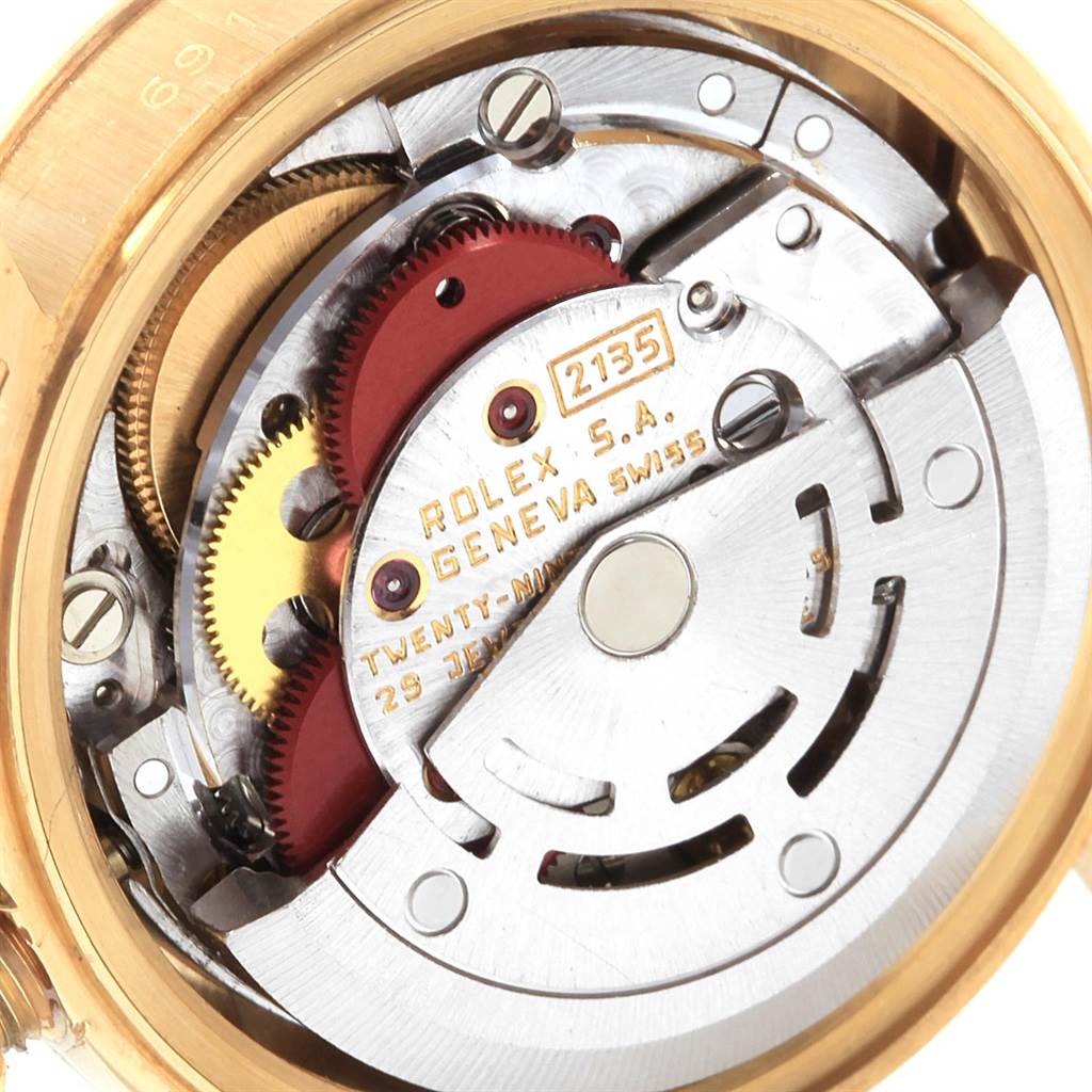 The image shows a close-up of the movement inside a Rolex President 69178 Women
s Yellow Gold Silver Dial 69178 Women
s Yellow Gold Silver Dial watch, highlighting its intricate gears and components.