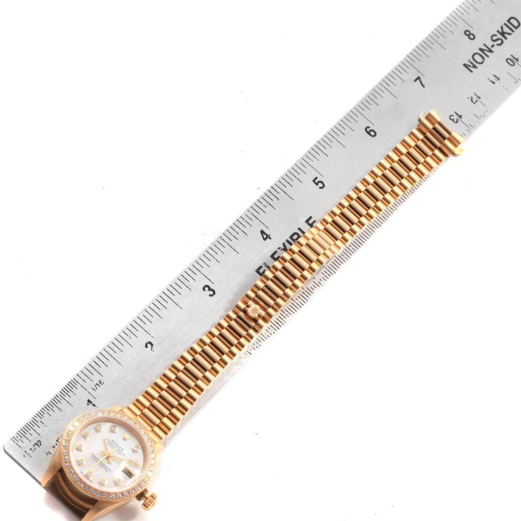 This image shows the Rolex President 79138 Women's Yellow Gold Mother of Pearl Dial 79138 Women's Yellow Gold Mother of Pearl Dial model watch laid flat next to a ruler, highlighting its band and face.