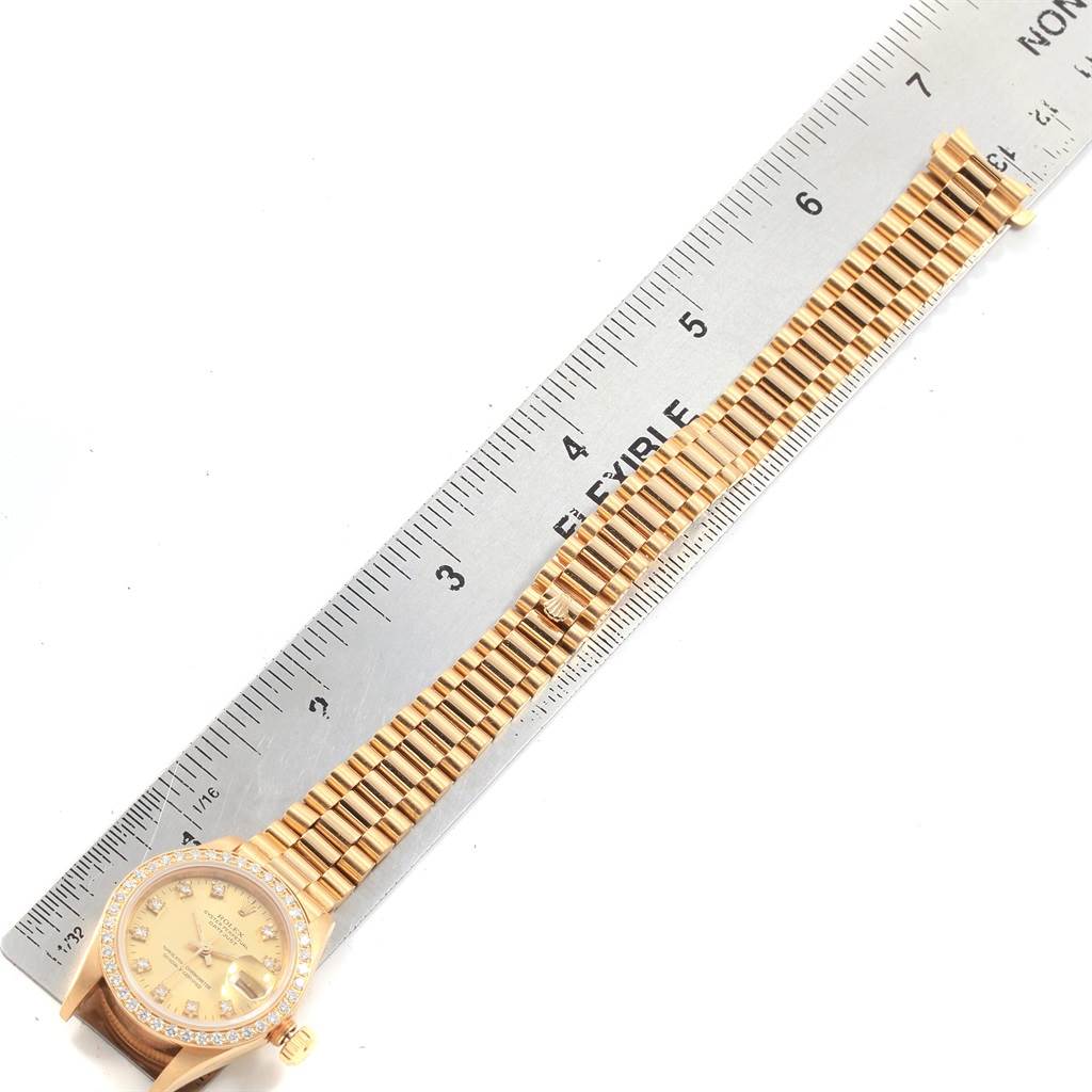 This image shows a Rolex President 69178 Women
s Yellow Gold Champagne Dial 69178 Women
s Yellow Gold Champagne Dial model watch placed alongside a ruler for measurement, highlighting the full band and face.