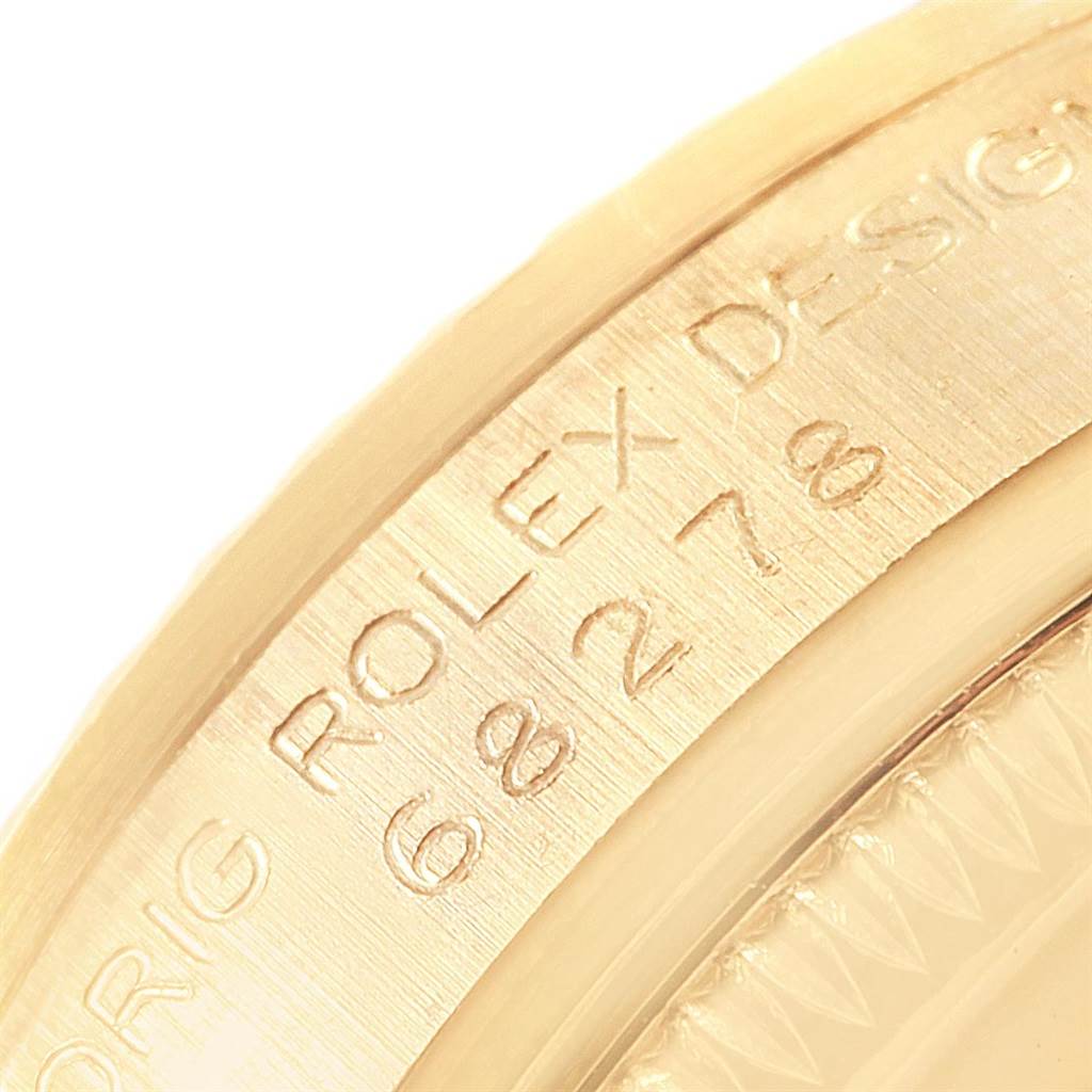 This close-up image shows the engraved text and part of the bezel of a Rolex President 68278 Women's Yellow Gold White Dial 68278 Women's Yellow Gold White Dial model watch.