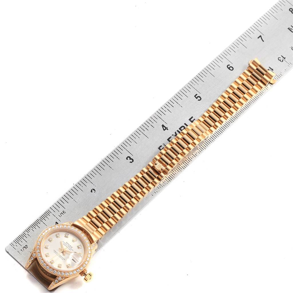 The image shows a Rolex President 69158 Women's Yellow Gold Silver Dial 69158 Women's Yellow Gold Silver Dial model watch lying flat with its entire band and face visible next to a ruler for scale.