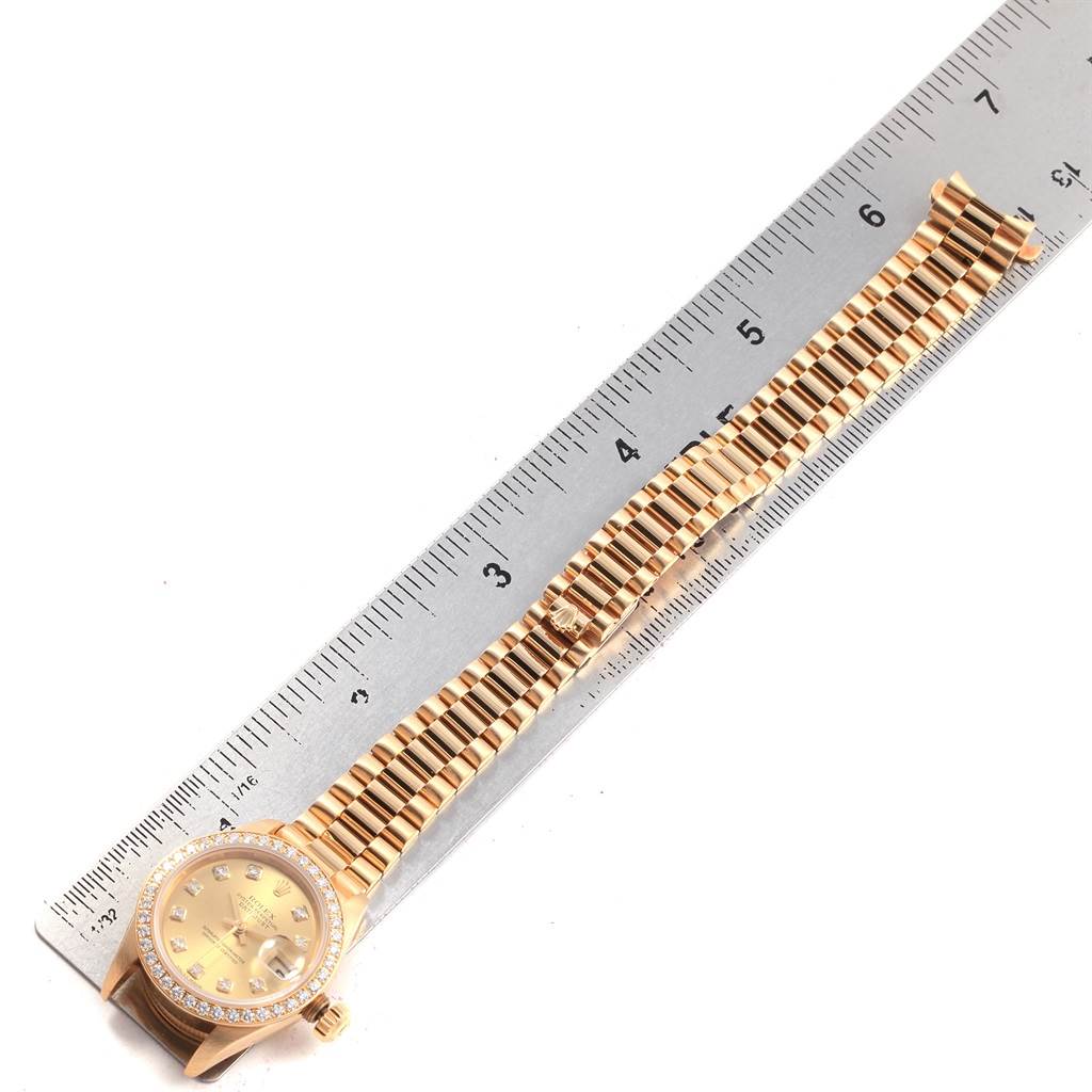 The Rolex President 79138 Women's Yellow Gold Champagne Dial 79138 Women's Yellow Gold Champagne Dial model watch is shown laid flat with a metal ruler, displaying the face, bracelet, and clasp.