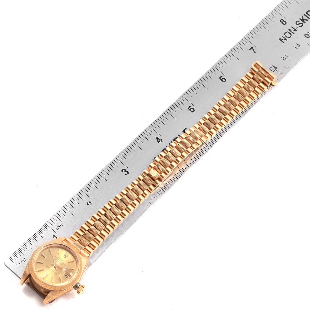 The image shows a Rolex President 6927 Women's Yellow Gold Champagne Dial 6927 Women's Yellow Gold Champagne Dial model watch laid flat alongside a ruler, displaying the watch face and bracelet.