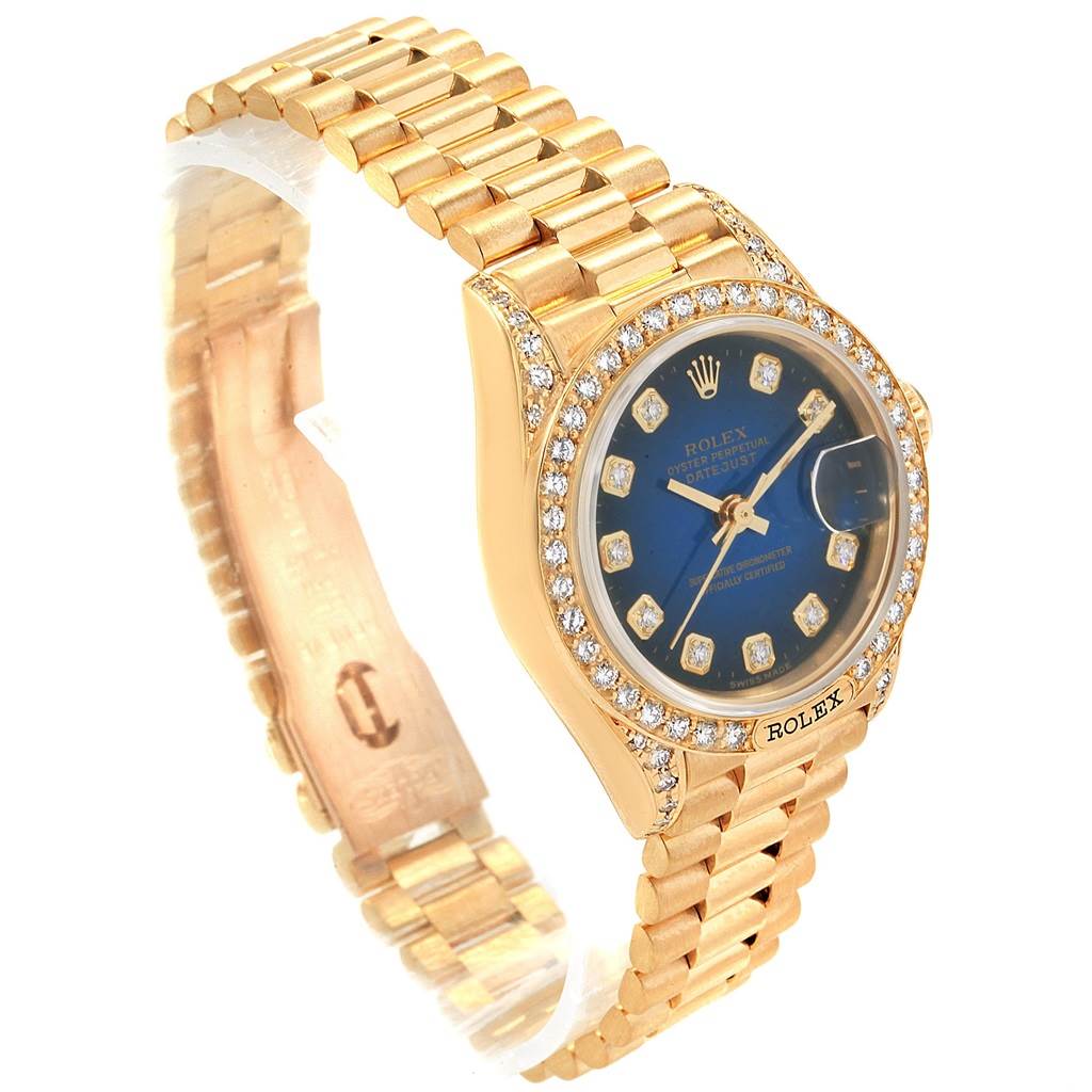 The image shows a Rolex President 69158 Women's Yellow Gold Blue Dial 69158 Women's Yellow Gold Blue Dial model watch at an angled view, highlighting the gold strap, diamond bezel, and blue dial.