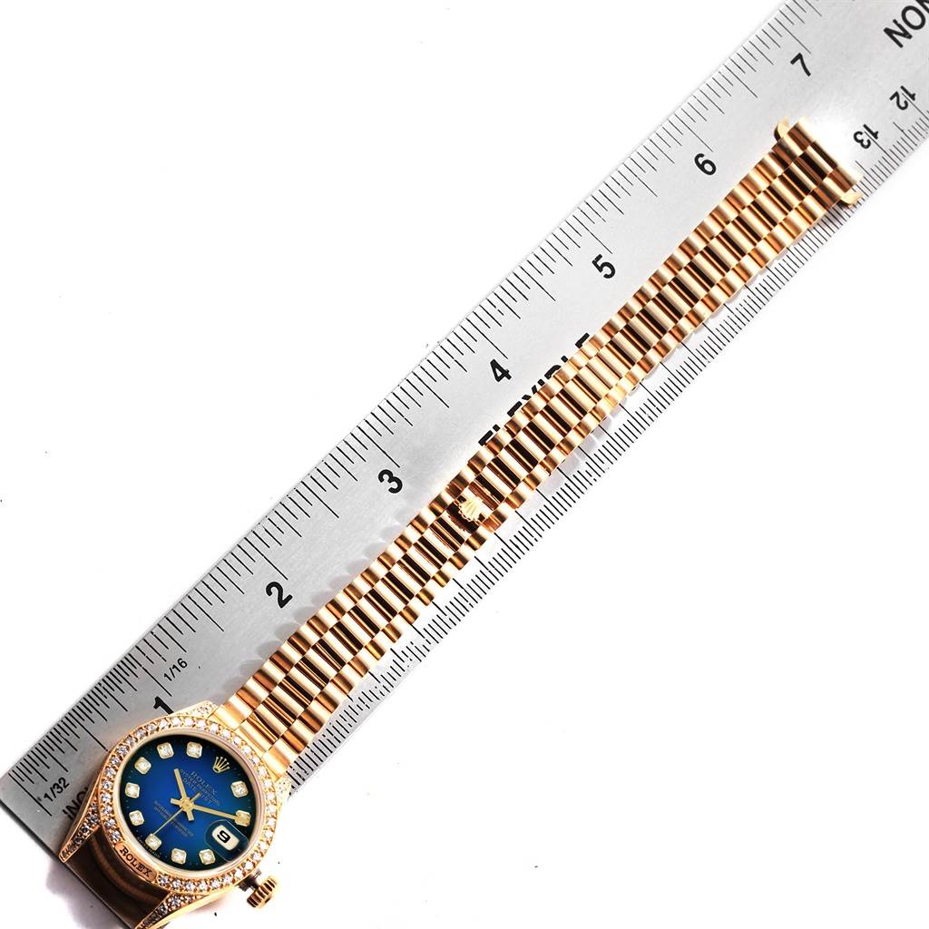 The Rolex President 69158 Women's Yellow Gold Blue Dial 69158 Women's Yellow Gold Blue Dial watch is shown from a top-down angle, displaying its face, bezel, and bracelet alongside a ruler for scale.