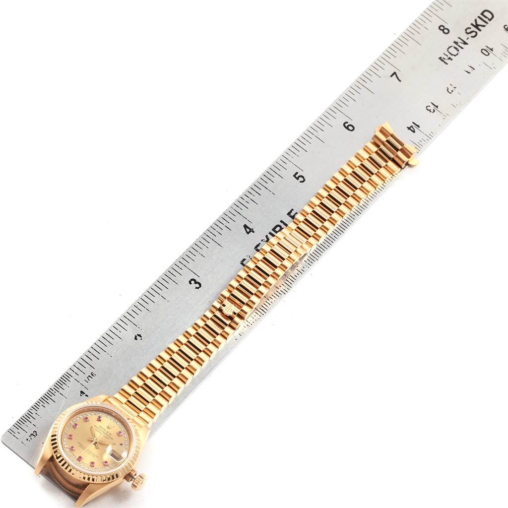 The Rolex President 69178 Women
s Yellow Gold Champagne Dial 69178 Women
s Yellow Gold Champagne Dial model watch is shown from above, displaying its dial, crown, and full bracelet alongside a ruler for size reference.