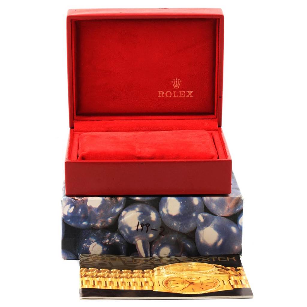 This image shows an empty red Rolex box for the President model and a part of a Rolex catalog.