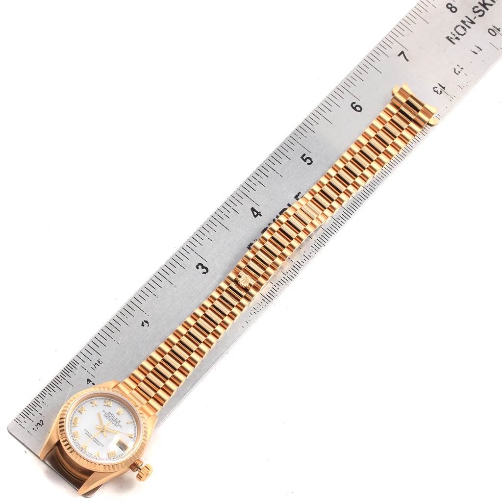 The image shows a top-down view of a Rolex President 69178 Women
s Yellow Gold Mother of Pearl Dial 69178 Women
s Yellow Gold Mother of Pearl Dial model watch, including the face, bezel, and gold bracelet, next to a ruler.