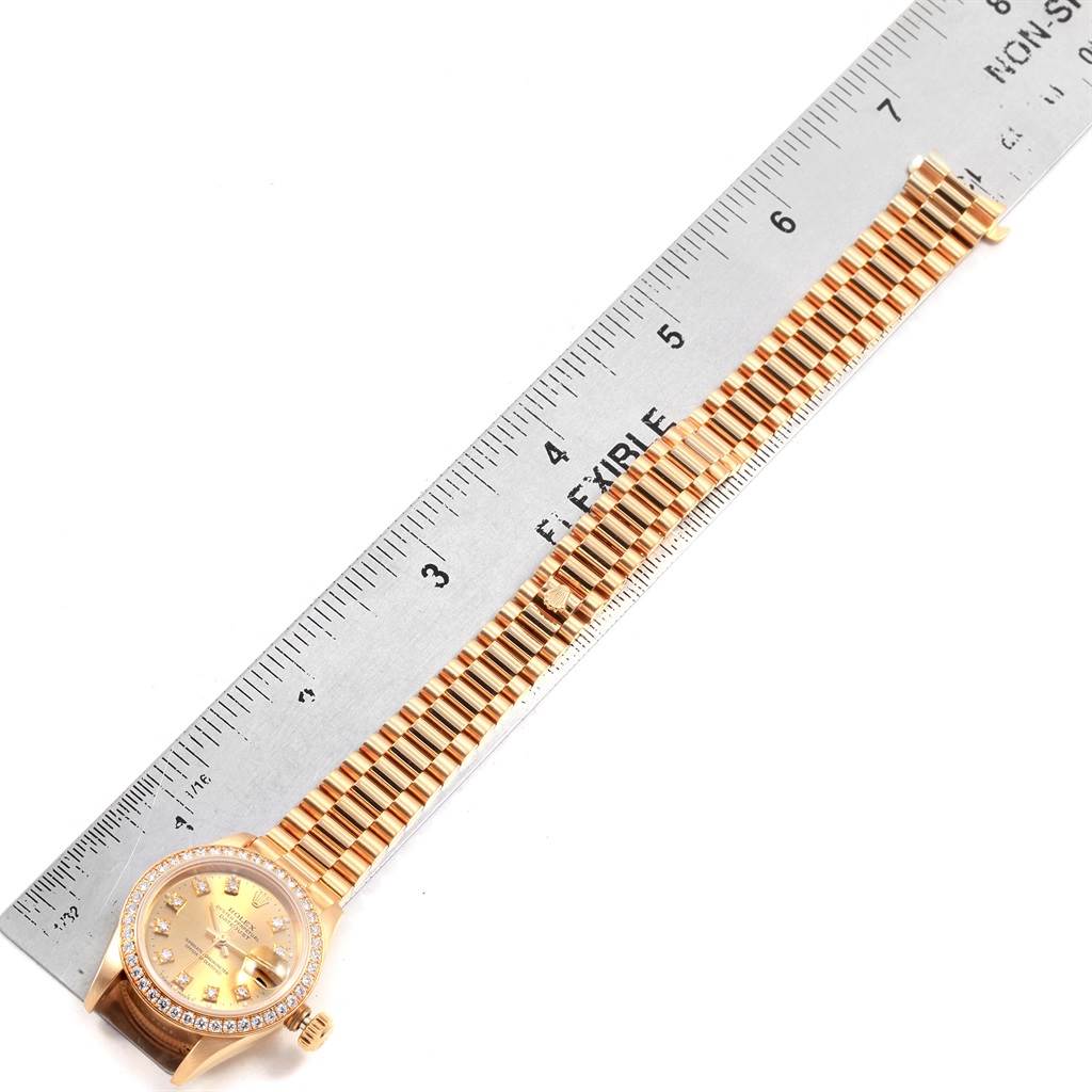 The image shows a top-down view of a Rolex President 69178 Women
s Yellow Gold Champagne Dial 69178 Women
s Yellow Gold Champagne Dial watch, highlighting its face, band, and bezel alongside a ruler for scale.
