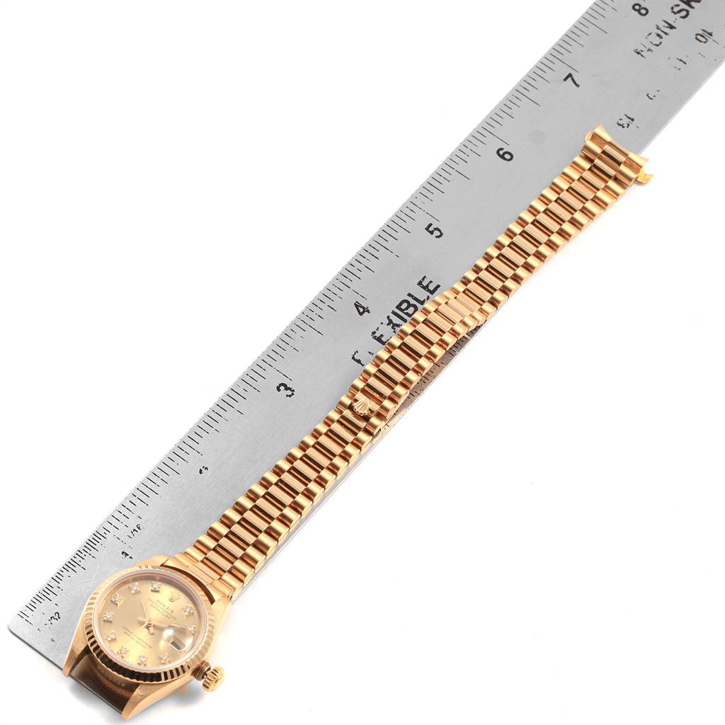 The Rolex President 69178 Women
s Yellow Gold Champagne Dial 69178 Women
s Yellow Gold Champagne Dial model watch is shown from a top-down angle, displaying its dial, case, and bracelet next to a ruler.