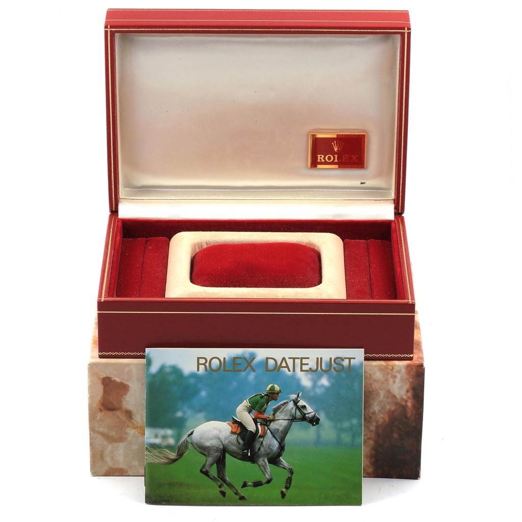 This image shows an open Rolex watch case for the President model, along with a Rolex Datejust card placed in front.