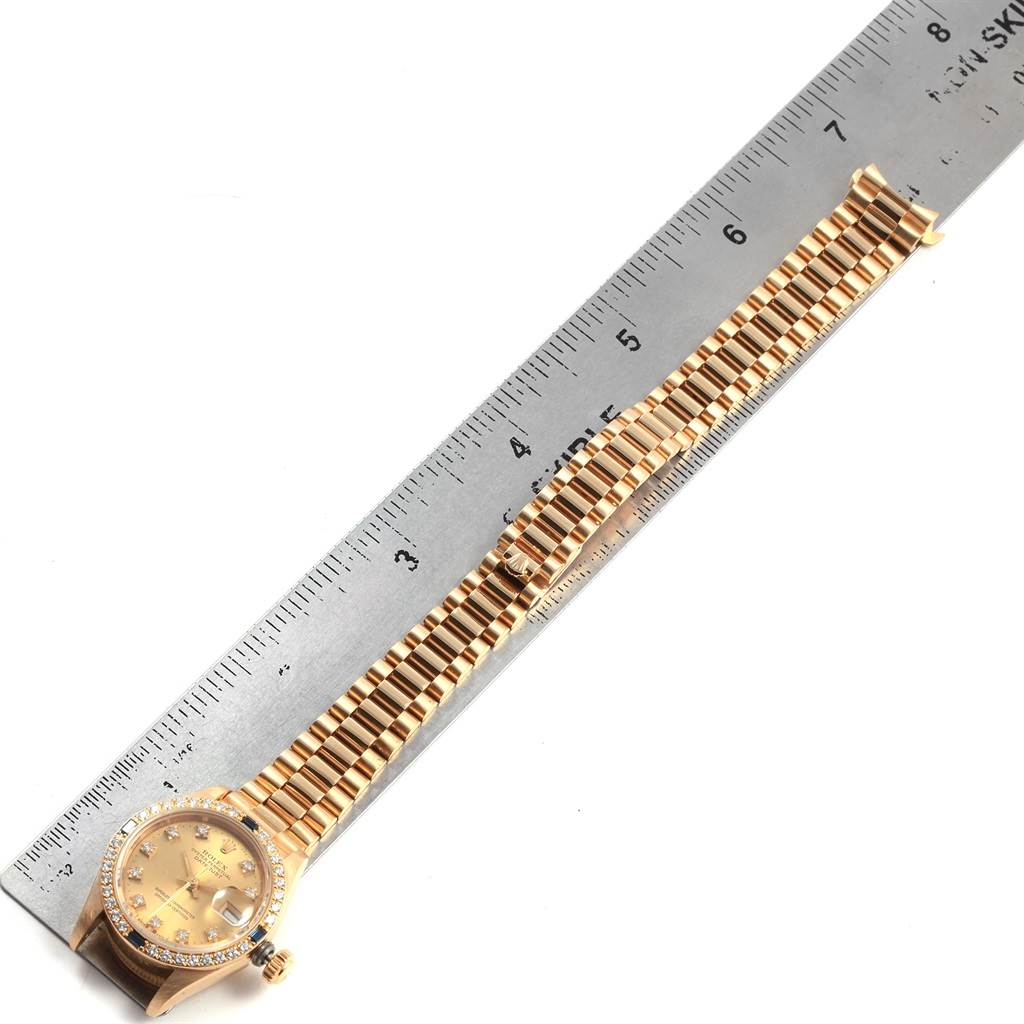 This image shows the President model by Rolex laid flat with its bracelet extended next to a ruler for scale.
