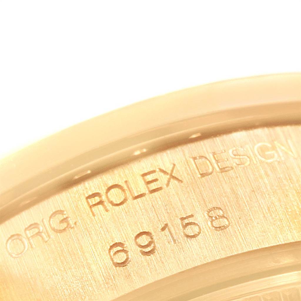The image shows a close-up of the case back of a Rolex President 69158 Women
s Yellow Gold Mother of Pearl Dial 69158 Women
s Yellow Gold Mother of Pearl Dial model, highlighting the engraved Rolex design and model number.