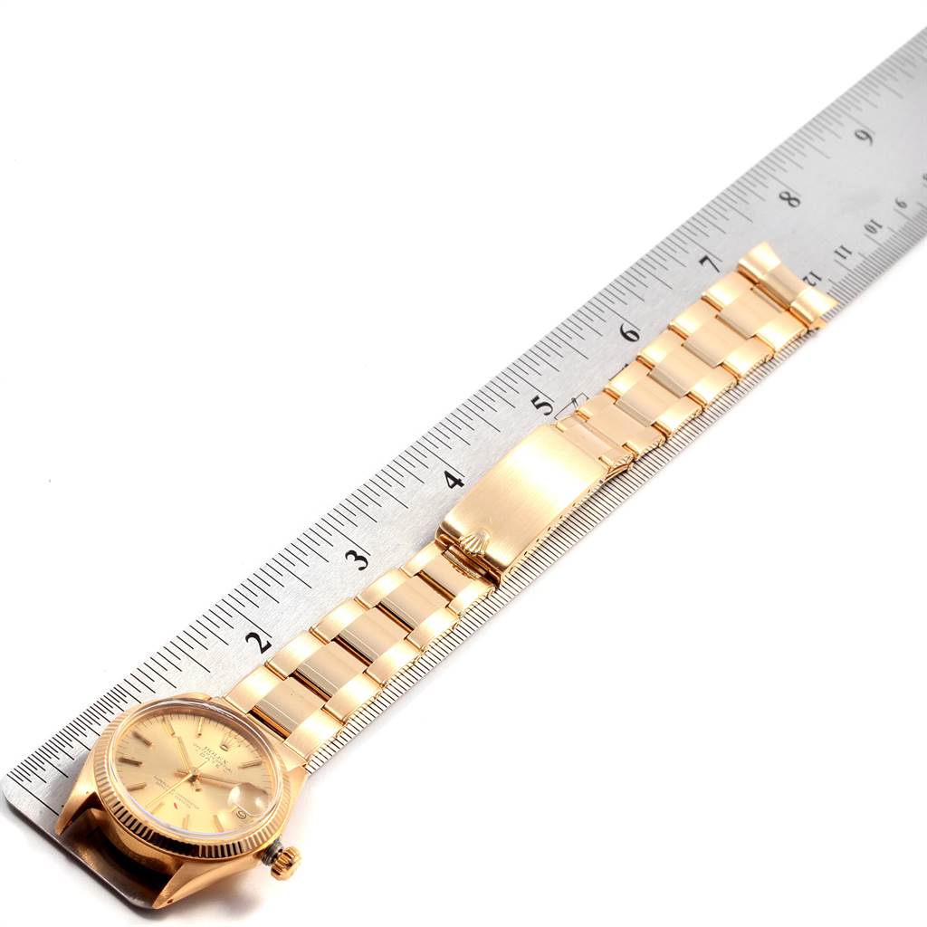 The image shows a top view of a gold Rolex President 6827 Women
s Yellow Gold Champagne Dial 6827 Women
s Yellow Gold Champagne Dial model watch next to a ruler, highlighting the bracelet and face.