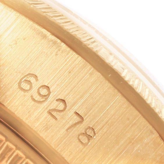 This close-up of a Rolex President 69278 Women
s Yellow Gold Champagne Dial 69278 Women
s Yellow Gold Champagne Dial model watch shows a partial view of the gold case with engraved numbers.