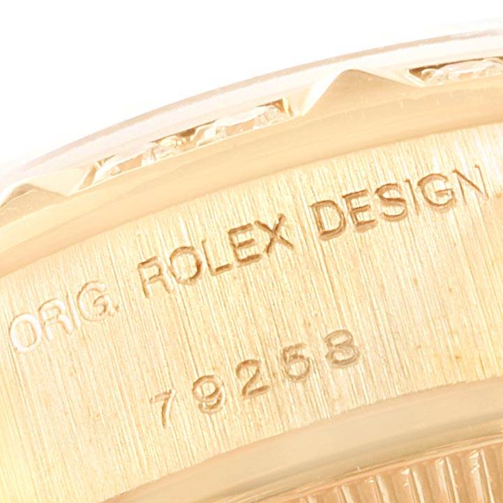 This close-up image shows the side of the case of a Rolex President 79258 Women's Yellow Gold Beige Dial 79258 Women's Yellow Gold Beige Dial watch, showcasing the engravings.