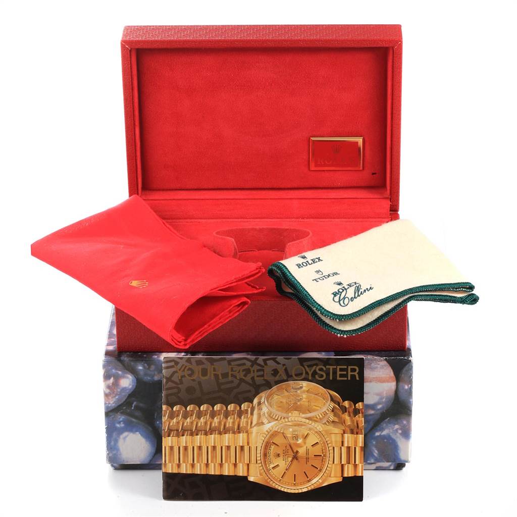 The image shows accessories for a Rolex President 79258 Women's Yellow Gold Beige Dial 79258 Women's Yellow Gold Beige Dial model watch, including a red box, cloths, and a brochure, from a frontal angle.