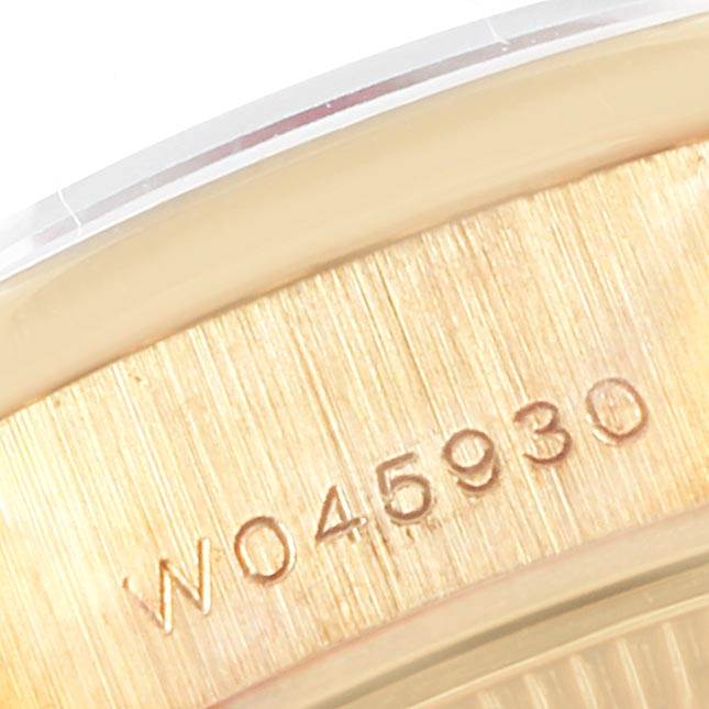 This close-up image of the Rolex President 69158 Women
s Yellow Gold White Dial 69158 Women
s Yellow Gold White Dial model watch shows a gold surface with the serial number "W045930" engraved on it.