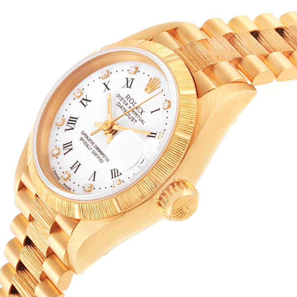 The image shows a side angle of the Rolex President 69278 Women
s Yellow Gold White Dial 69278 Women
s Yellow Gold White Dial model watch, highlighting its gold band, crown, and face with Roman numerals and gemstones.