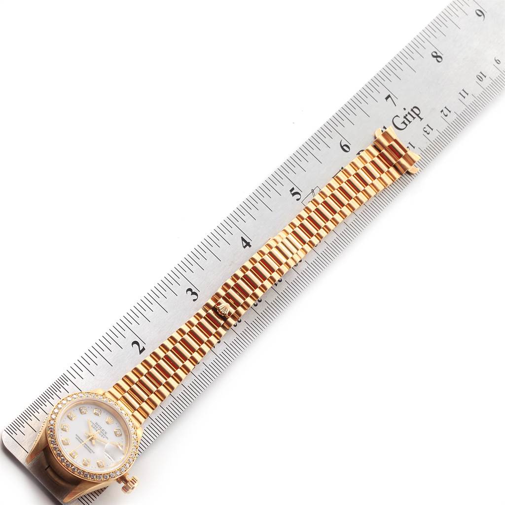 The image shows a President model Rolex watch placed alongside a ruler, highlighting its bracelet and face.