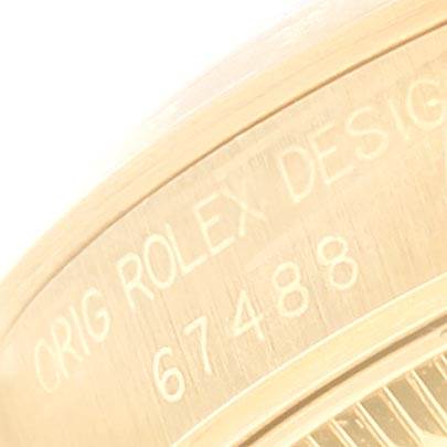 The image shows a close-up of the side of a Rolex President 67488 Women's Yellow Gold Blue Dial 67488 Women's Yellow Gold Blue Dial model, focusing on the serial and design numbers engraved on it.