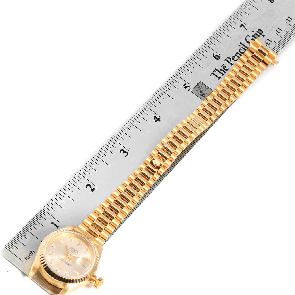 This image shows a top view of a Rolex President 69178 Women
s Yellow Gold Champagne Dial 69178 Women
s Yellow Gold Champagne Dial model watch laid next to a ruler, with the face and bracelet visible.