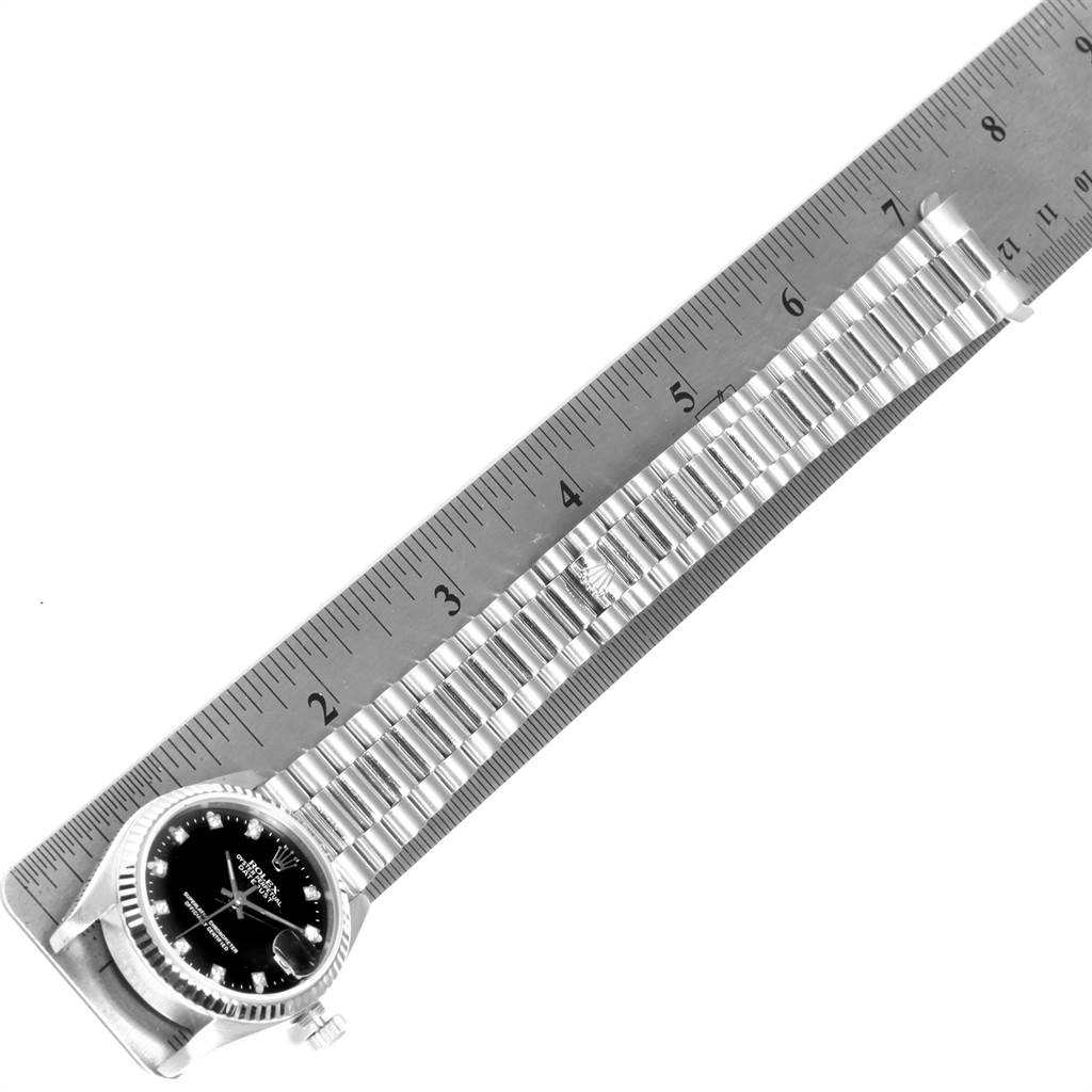 The image shows the President model Rolex watch laid flat next to a ruler, displaying its face and bracelet.