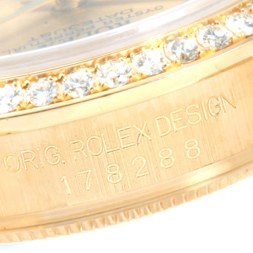 The image shows a close-up of the bezel and side case of a Rolex President 178288 Women
s Yellow Gold Champagne Dial 178288 Women
s Yellow Gold Champagne Dial model watch, highlighting its diamonds and engraved design.