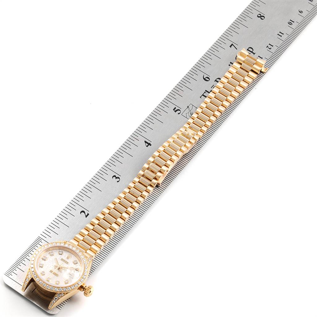 This image shows a Rolex President 79158 Women's Yellow Gold Silver Dial 79158 Women's Yellow Gold Silver Dial model watch with a gold bracelet laid next to a ruler for measurement.