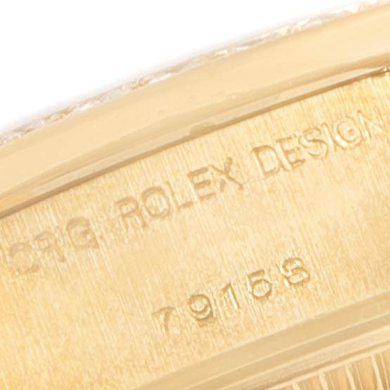 This close-up image of a Rolex President 79158 Women's Yellow Gold Silver Dial 79158 Women's Yellow Gold Silver Dial model watch shows part of the case with "ROLEX DESIGN" and model number engraved.