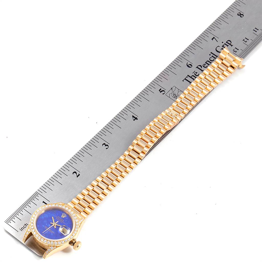 The image shows a Rolex President 69158 Women's Yellow Gold Blue Dial 69158 Women's Yellow Gold Blue Dial model watch laid flat beside a ruler, displaying its dial, bezel, crown, and full bracelet.