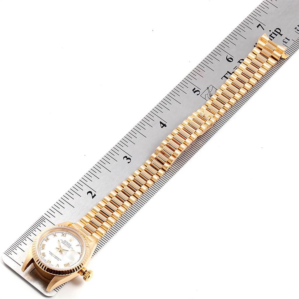 The image shows a Rolex President 69178 Women
s Yellow Gold White Dial 69178 Women
s Yellow Gold White Dial watch with its gold bracelet laid flat against a ruler for measurement.