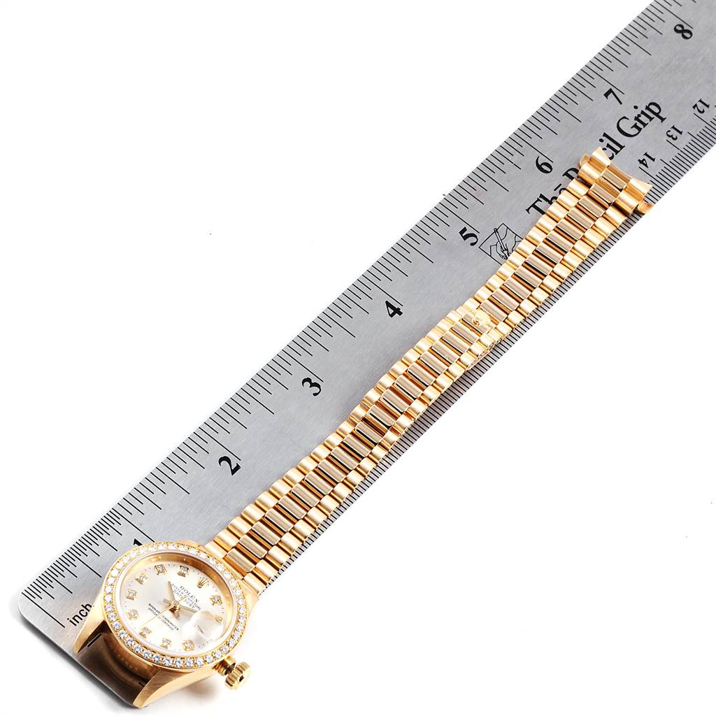 The image shows a gold Rolex President 69138 Women's Yellow Gold Silver Dial 69138 Women's Yellow Gold Silver Dial model watch laid next to a ruler for measurement, displaying the face and bracelet at a slight angle.