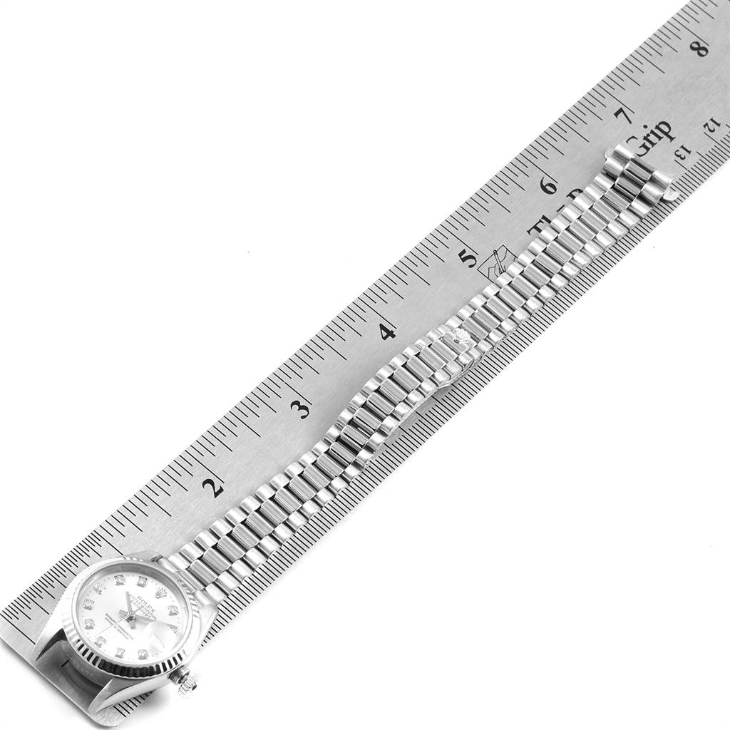 The image shows a top-down view of a Rolex President 69179 Women's White Gold Silver Dial 69179 Women's White Gold Silver Dial model watch and its bracelet next to a ruler for scale.
