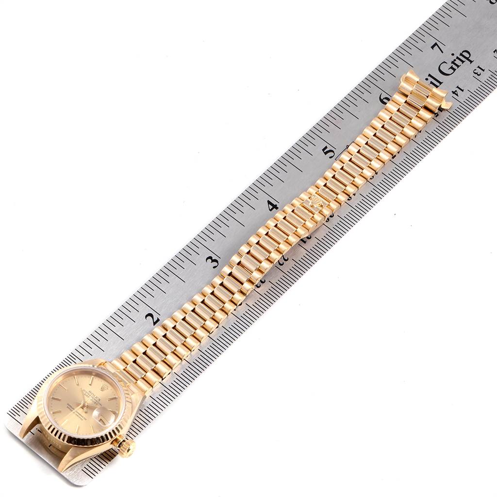 The image shows a Rolex President 69178 Women
s Yellow Gold Champagne Dial 69178 Women
s Yellow Gold Champagne Dial watch laid flat along a ruler, highlighting the face, crown, and full bracelet.