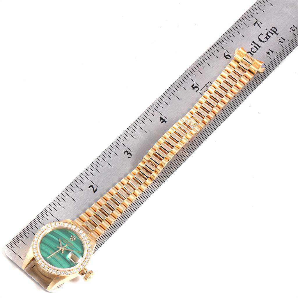 The image shows a Rolex President 69138 Women's Yellow Gold Green Dial 69138 Women's Yellow Gold Green Dial model watch from a top-down angle, displaying its face, bezel, crown, and bracelet alongside a ruler.