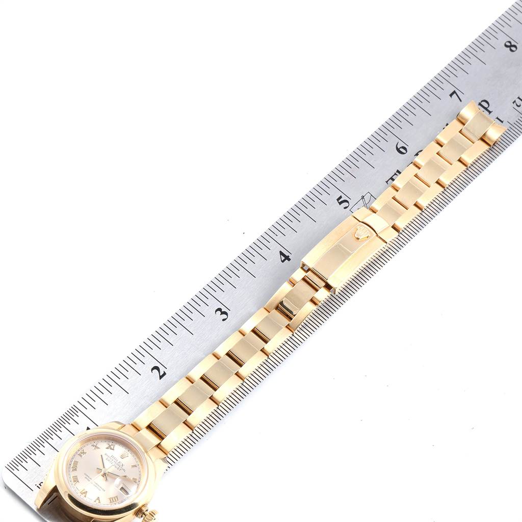 The Rolex President 179168 Women
s Yellow Gold Champagne Dial 179168 Women
s Yellow Gold Champagne Dial model watch is shown from a top-down angle, displaying its dial, bracelet, and clasp next to a ruler.
