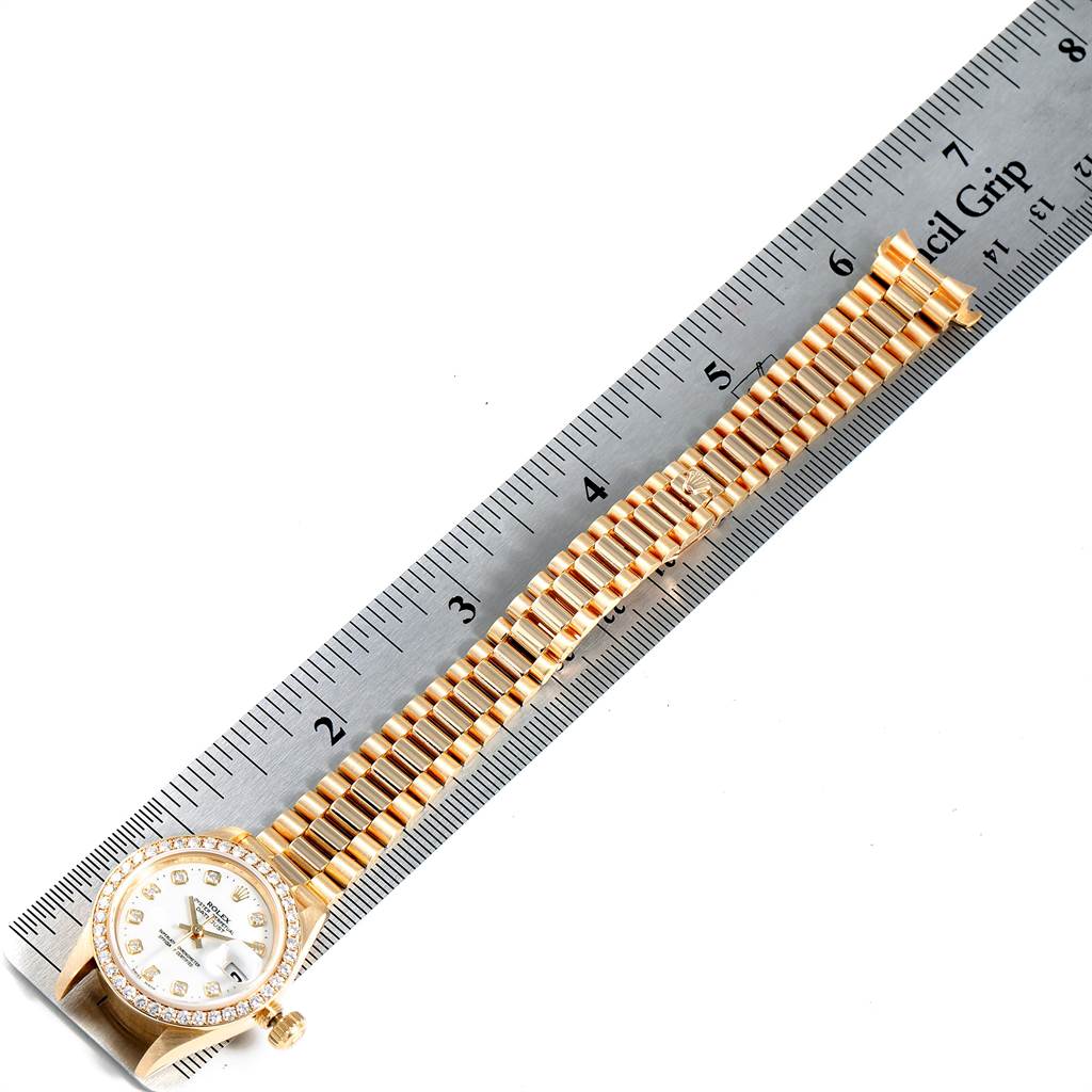 A Rolex President 69138 Women
s Yellow Gold White Dial 69138 Women
s Yellow Gold White Dial model watch is shown from the top, including the face, bezel, and full bracelet, with a ruler for scale.