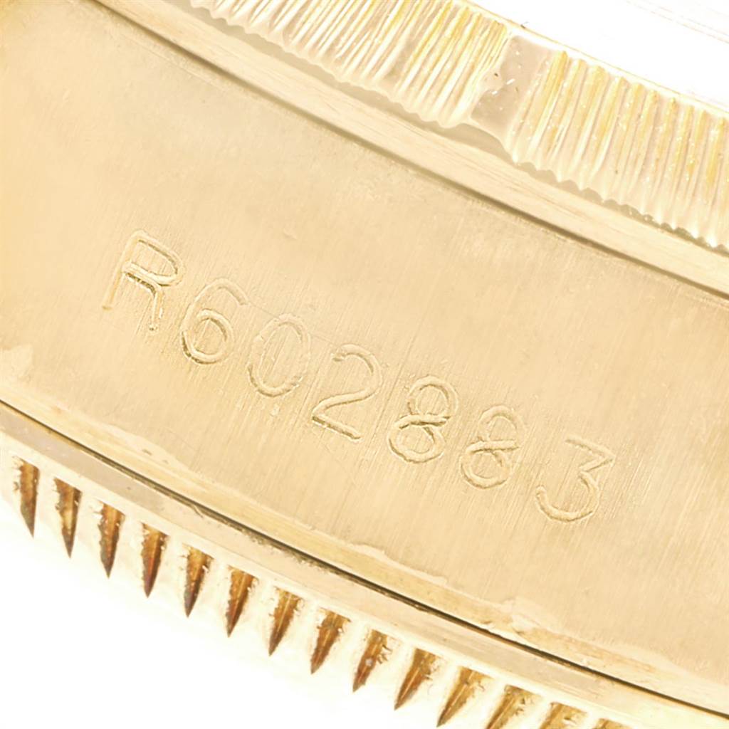 This close-up image shows the engraved serial number and part of the fluted bezel of a Rolex President 69278 Women's Yellow Gold Blue Dial 69278 Women's Yellow Gold Blue Dial model watch.