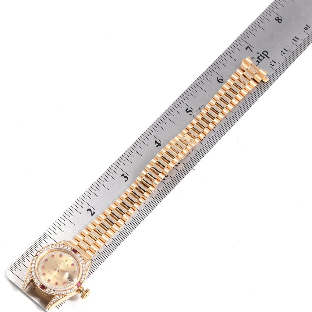 The image shows a Rolex President 69238 Women
s Yellow Gold Champagne Dial 69238 Women
s Yellow Gold Champagne Dial model watch with a gold bracelet and diamond bezel, placed alongside a ruler.