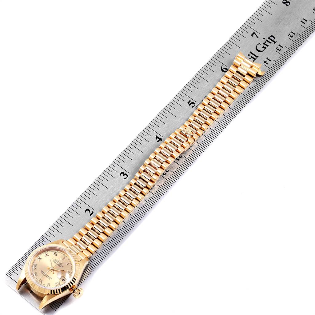 The Rolex President 69178 Women's Yellow Gold Champagne Dial 69178 Women's Yellow Gold Champagne Dial model watch is shown from a top-down angle, displaying the face, band, and crown next to a ruler.