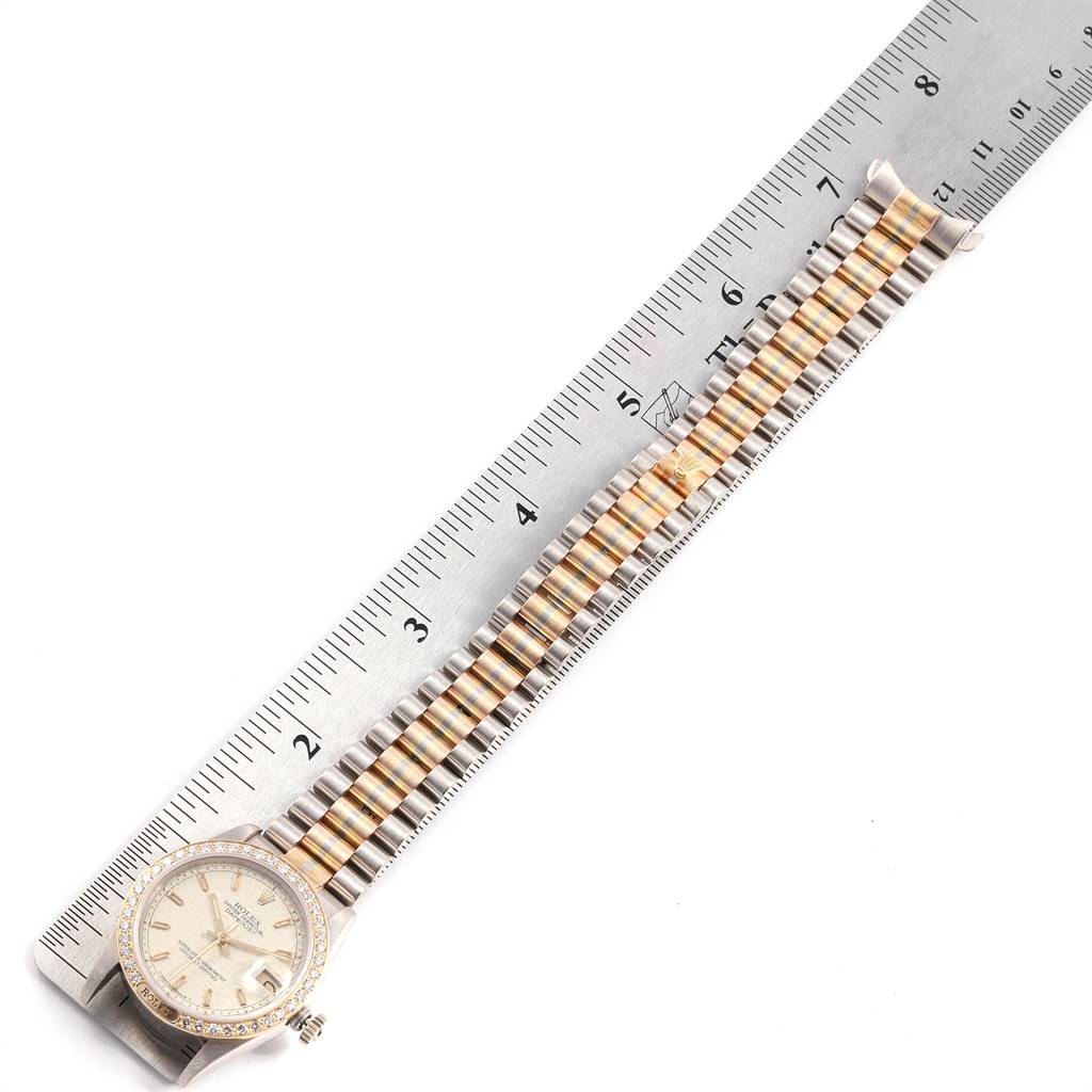 The image shows a Rolex President 68149 Women's White Gold Beige Dial 68149 Women's White Gold Beige Dial model watch placed parallel to a ruler, displaying its gold and silver bracelet and watch face from a top-down angle.