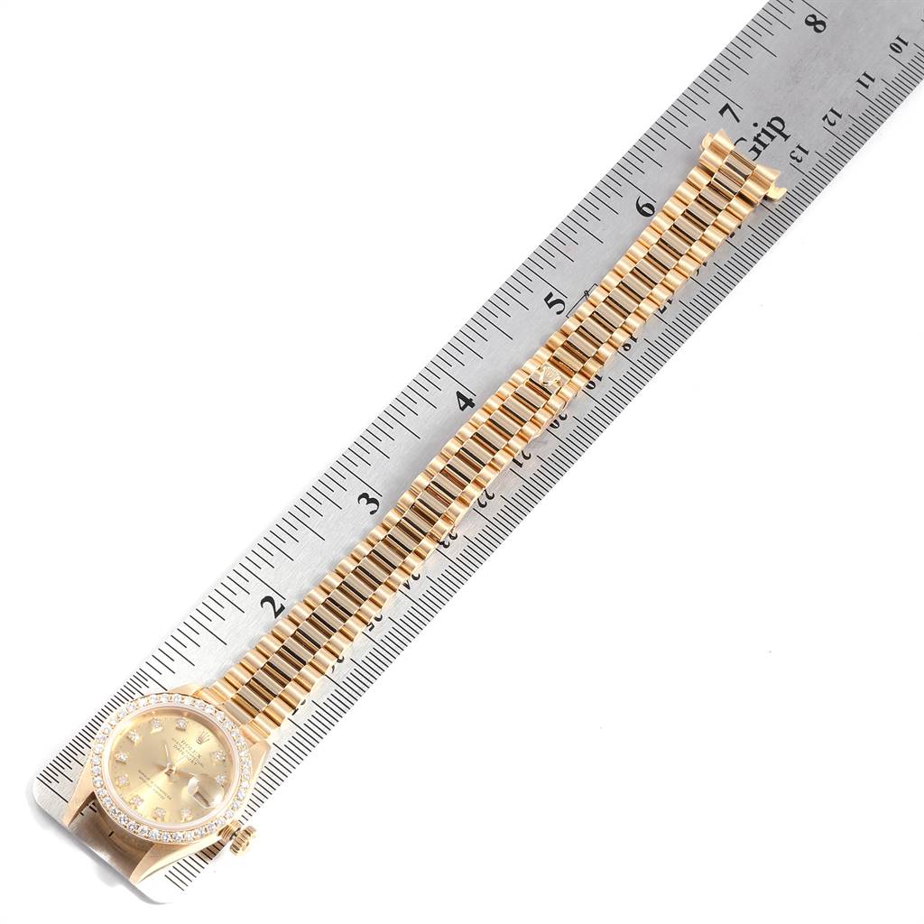 The image shows a gold Rolex President 69138 Women
s Yellow Gold Champagne Dial 69138 Women
s Yellow Gold Champagne Dial model watch against a ruler, displaying the watch face and full bracelet laid flat.