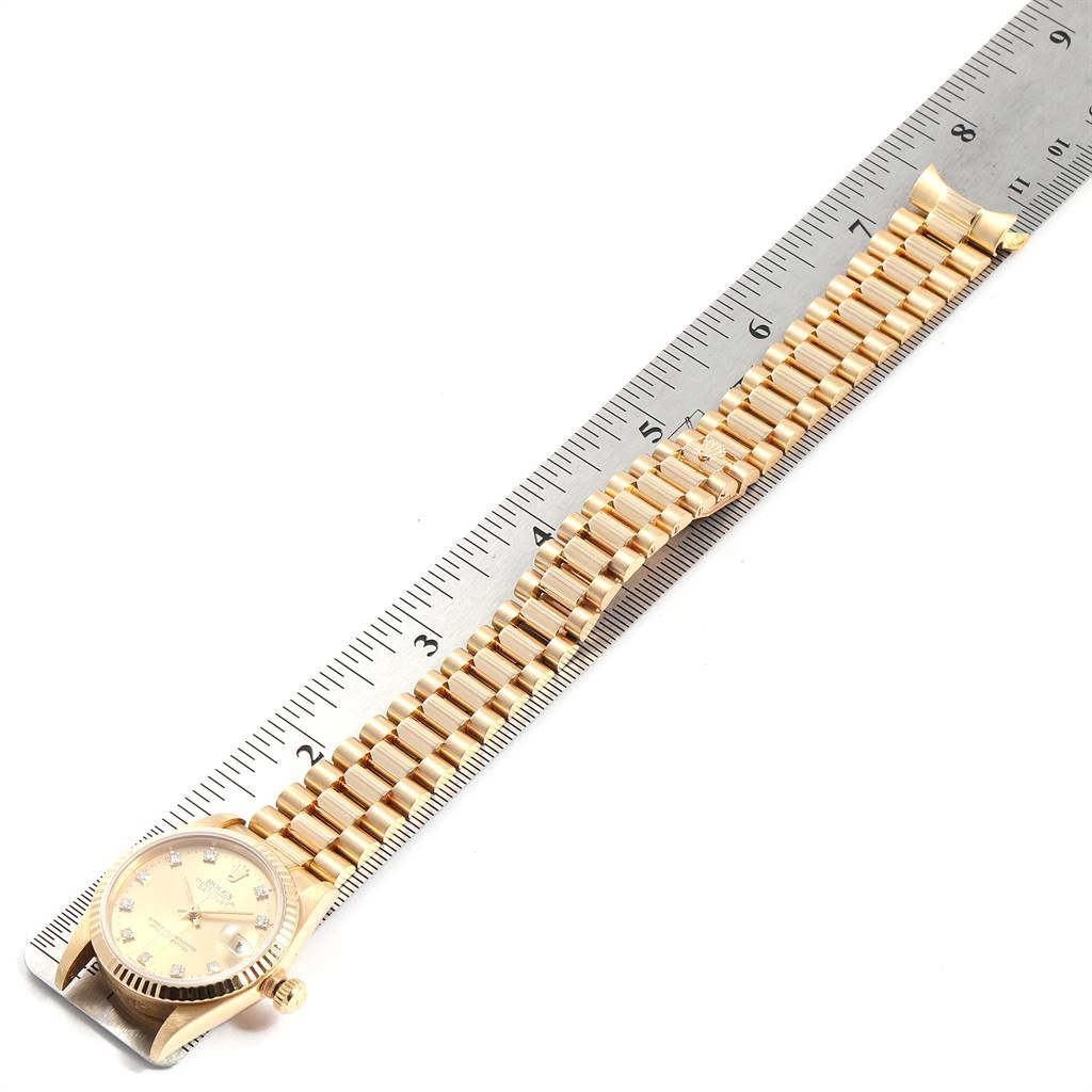 The image shows the Rolex President 68278 Women
s Yellow Gold Champagne Dial 68278 Women
s Yellow Gold Champagne Dial model watch laid against a ruler, displaying its full length and bracelet.