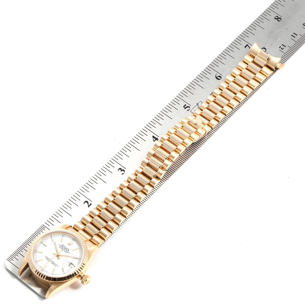 The image shows a top-down view of a Rolex President 68278 Women
s Yellow Gold White Dial 68278 Women
s Yellow Gold White Dial model watch, highlighting the dial and gold bracelet with a ruler for scale.