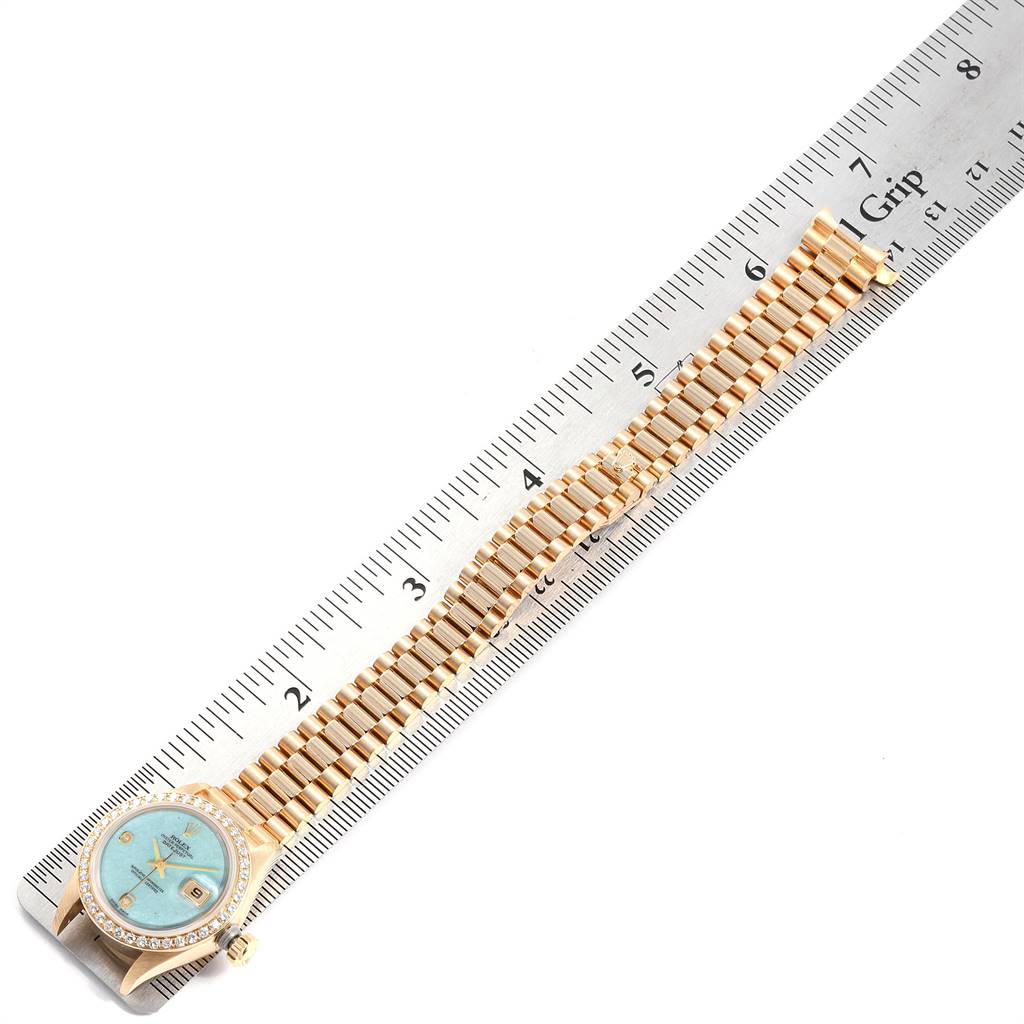 The Rolex President 69138 Women's Yellow Gold Blue Dial 69138 Women's Yellow Gold Blue Dial model watch is shown from above, highlighting its face, bezel, and bracelet on a ruler for measurement.