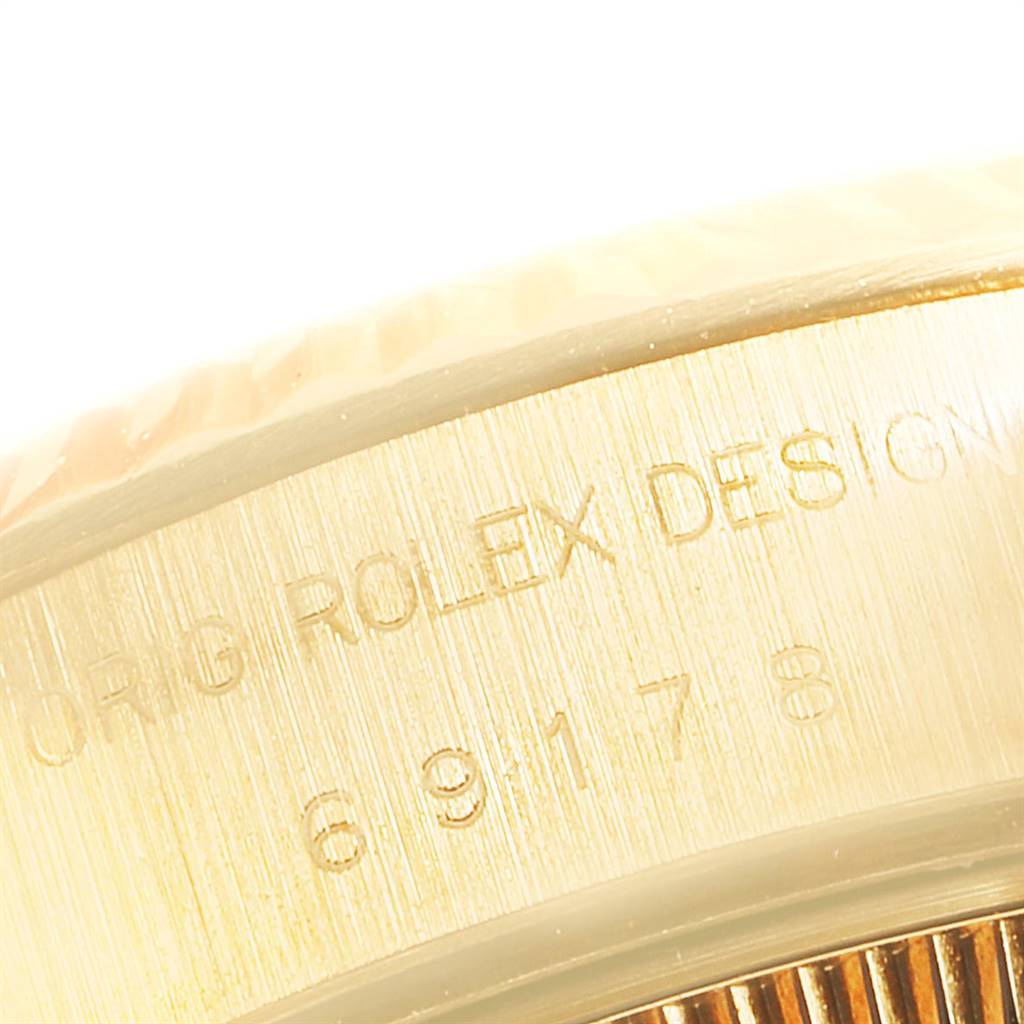 This close-up image shows the engraved side of the bezel of a Rolex President 69178 Women
s Yellow Gold Champagne Dial 69178 Women
s Yellow Gold Champagne Dial watch.