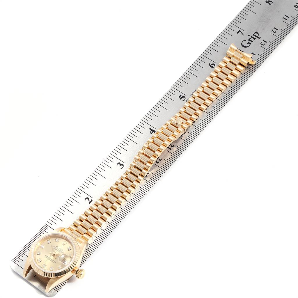 The Rolex President 69178 Women
s Yellow Gold Champagne Dial 69178 Women
s Yellow Gold Champagne Dial model watch is shown at an angle, displaying the face, bracelet, and measured against a ruler.